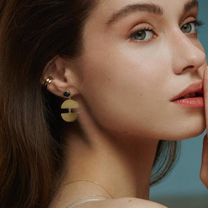 The 14K Solid Gold Elegant Dangle Drop Earrings of the Moonlight Collection showcase a circular black enamel stone at the top and a split semicircular design below, linked together to form a graceful drop. Their glossy finish and post backings enhance the elegance of these hypoallergenic accessories.