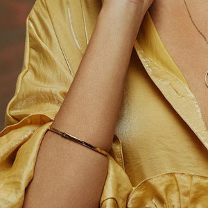 The 14K Solid Gold Plain Shiny Bangle Bracelet from the Harmony Collection offers a simple, elegant design with a smooth finish and a small clasp for secure fastening. Its circular shape boasts a shiny surface that reflects light softly.