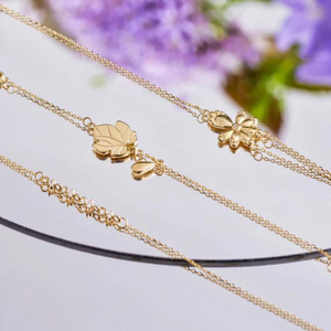 Introducing the 14K Solid Gold Diamond Eucalyptus Flower Bracelet from the Chloris Collection: a delicate bracelet featuring a fine chain and small linked charms at its center. This exquisite piece includes an adjustable clasp complemented by an extension chain, finishing elegantly with a small round disc.