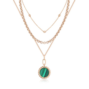 The 14K Solid Gold Natural Malachite 3 Layer Necklace from the Endless Collection displays multiple chains of varying thickness, crafted from real solid yellow gold. The longest chain gracefully features a circular pendant adorned with a natural malachite gemstone, encircled by a twisted gold border, and is meticulously designed to be hypoallergenic.