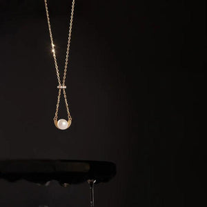 Introducing the 14K Solid Gold Natural Pearl Necklace from the Elegance Collection. This hypoallergenic necklace showcases a natural pearl elegantly set within a gold arc, suspended from a delicate chain. A small diamond cluster adorns the top, adding a touch of sophistication. The piece is beautifully displayed against a white background.