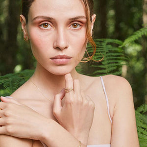 The 14K Solid Gold The Leaf Gold Ring from the Chloris Collection features a graceful leaf-like motif adorned with lab-grown rubies in the center. Its sleek band enhances the intricate detailing, crafted using sustainable methods.