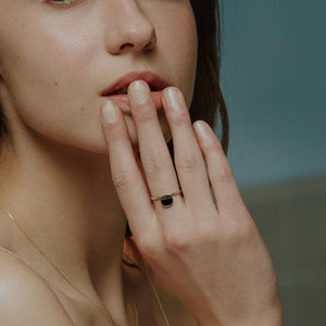 The "14K Solid Gold The First Quarter Moon Black Enamel Ring" from the Moonlight Collection showcases a minimalist and modern design, featuring a round black enamel stone partially overlaid with elegant 14K solid gold craftsmanship. Inside the band, engraved details highlight the meticulous Runda handcrafting.