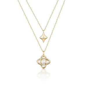 Part of the Elegance Collection, the 14K Solid Gold Natural Pearl Double Layer Necklace features a hypoallergenic design with two layers: the upper chain displays a small diamond-shaped pendant while the lower chain highlights an intricate intertwined design holding a natural pearl, all set against a white background.