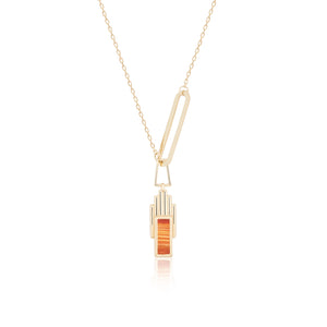 Introducing the Achates Collection: a 14K solid gold necklace with a geometric pendant that boasts vertical elements of orange and yellow gold. This elegant piece is accented by a natural carnelian gemstone, while an elongated link above the pendant provides a modern flair to its design.
