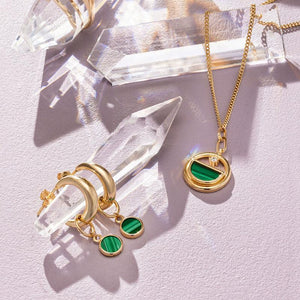 The 14K Solid Gold Malachite Hoop Earrings from the Endless Collection feature a pair of gleaming yellow gold hoops with small green circular pendants. Set against a white backdrop, these hypoallergenic earrings highlight their lustrous finish and sophisticated design.