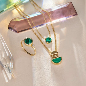 Introducing the 14K Solid Gold Double Layer Malachite Necklace from the Endless Collection. This exquisite piece is crafted from 14K yellow gold and features two captivating malachite gemstone pendants: a small round stone on the shorter chain and a larger semi-circle stone on the longer chain. The necklace's simple yet elegant chains beautifully accentuate the vibrant colors of its pendants.