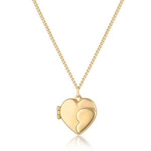 A 14K solid gold heart-shaped photo locket medallion from the Timeless Collection hangs gracefully from a delicate chain. The handcrafted locket features a smooth, reflective surface with a curved line design that suggests it can open. Hypoallergenic and elegantly styled, this exquisite piece is beautifully displayed against a white background.