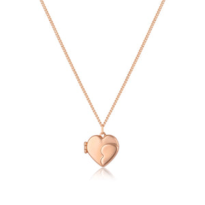 A 14K solid gold heart-shaped photo locket medallion from the Timeless Collection hangs gracefully from a delicate chain. The handcrafted locket features a smooth, reflective surface with a curved line design that suggests it can open. Hypoallergenic and elegantly styled, this exquisite piece is beautifully displayed against a white background.