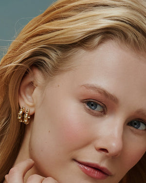 Introducing the 14K Solid Gold The Civilizations of the Sun Stud Earrings from our Helios Collection. These earrings feature a distinctive circular design adorned with round protrusions along the edges. Displaying one earring from the side and another from the front, they are expertly crafted using Runda handcrafting techniques and feature a reflective, polished finish.