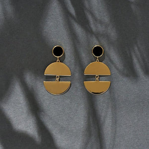 The 14K Solid Gold Elegant Dangle Drop Earrings of the Moonlight Collection showcase a circular black enamel stone at the top and a split semicircular design below, linked together to form a graceful drop. Their glossy finish and post backings enhance the elegance of these hypoallergenic accessories.