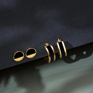 A pair of 14K Solid Gold Black Enamel Round Hoop Earrings from the Moonlight Collection, featuring one with a side view and the other with a full circle profile, elegantly designed and hypoallergenic against a white background.