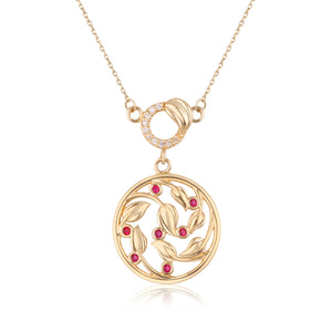 The 14K Solid Gold Lab-Grown Diamond Ivy Necklace from the Chloris Collection features a circular pendant with an intricate leaf design and lab-grown ruby gemstones. Its delicate chain is accented with a gold clasp adorned with small white stones, and the pendant boasts a reflective surface beneath it.