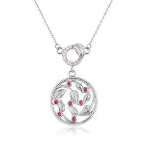 The 14K Solid Gold Lab-Grown Diamond Ivy Necklace from the Chloris Collection features a circular pendant with an intricate leaf design and lab-grown ruby gemstones. Its delicate chain is accented with a gold clasp adorned with small white stones, and the pendant boasts a reflective surface beneath it.