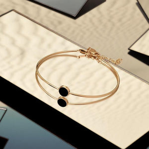 Introducing the 14K Solid Gold The Moon Effect Bangle Bracelet from the Moonlight Collection—a chic design accented with a minimalist round black feature and complemented by a delicately crafted dangling charm, attached by an adjustable short chain.