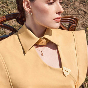 Achates Collection's 14K solid gold necklace showcases a modern and elegant design, featuring a distinctive pendant with both oval and rectangular elements, vibrant orange details, and a small rectangular agate gemstone.