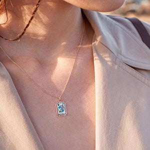 This elegant necklace from the Tarot Collection, named "The World," showcases a 14K solid gold pendant featuring an Earth illustration on a rectangular frame. The words "The World" are inscribed beneath, reminiscent of a tarot pendant. Both hypoallergenic and delicate, the pendant gracefully hangs from its chain.