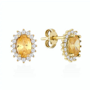 The 14K Solid Gold Oval Shaped Citrine Stud Earrings display vintage citrine gemstones, each set in a halo of small white diamonds. They feature a screw-back design and are presented against a plain white background.