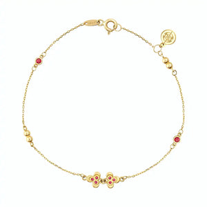 Introducing the 14K Solid Gold Ruby Leaf Bracelet from the Chloris Collection by RundaJewelryUs. This exquisite piece showcases a delicate chain design adorned with two small red floral motifs and three gold beads, reminiscent of the July birthstone. It features a secure lobster clasp and is elegantly finished with a circular tag at the end.