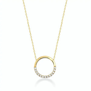 The 14K Gold Minimal Dainty Circle Necklace from RundaJewelryUs showcases a round pendant adorned with small diamonds embellishing the bottom half, producing a captivating sparkle. Set on a plain white background, its understated design accentuates the elegance and sophistication of this stunning jewelry piece.