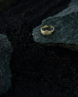 A 14K solid gold ring from the "Into the Woods" collection by Erdem Akan, featuring a textured, organic design on the band and meticulously handcrafted using sustainable methods.