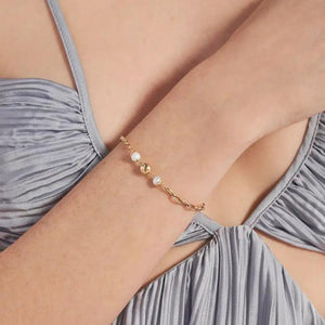 Introducing the "Elegance Collection" 14K Solid Gold Natural Pearl Bracelet. This exquisite piece showcases a chain design accented with two natural pearl-like beads and a centerpiece crafted from 14K solid gold. The lobster claw clasp ensures secure fastening and is hypoallergenic, making it suitable for sensitive skin.