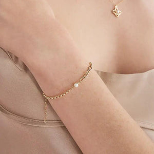 Presenting our 14K Solid Gold Natural Pearl Bracelet from the Elegance Collection, this exquisite piece showcases a blend of round and elongated links in stunning solid gold, decorated with two natural white pearls. Hypoallergenic and crafted with a secure clasp closure, it offers everyday elegance effortlessly.