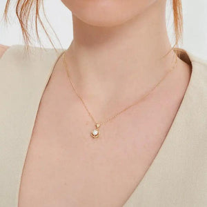 The 14K Solid Gold Natural Pearl Necklace from the Elegance Collection showcases a gold necklace with a delicate chain, featuring a heart-shaped link that holds a circular pendant. The pendant is designed with an intricate knot pattern encircling a single natural pearl. Crafted from real 14K solid yellow gold, this piece has a polished, hypoallergenic, and elegant appearance.