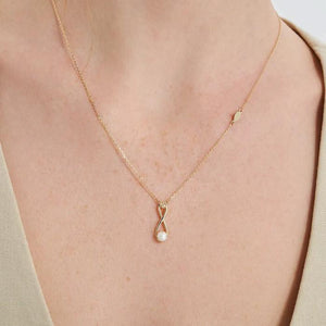 The 14K Solid Gold Natural Pearl Necklace from the Elegance Collection features an infinity-shaped pendant crafted from real solid yellow gold. The pendant beautifully displays a natural pearl at the bottom intersection and a small diamond at the top loop, all suspended on a simple, hypoallergenic chain.