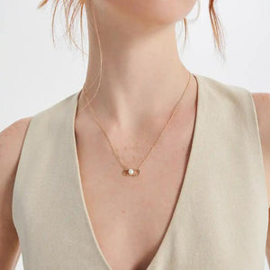 Part of the Elegance Collection, this 14K solid gold necklace features a unique pendant with a natural white pearl at its center, tastefully accented by two small round diamonds within an abstract geometric design.