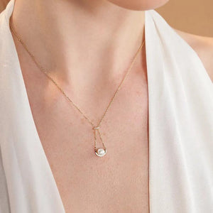 Introducing the 14K Solid Gold Natural Pearl Necklace from the Elegance Collection. This hypoallergenic necklace showcases a natural pearl elegantly set within a gold arc, suspended from a delicate chain. A small diamond cluster adorns the top, adding a touch of sophistication. The piece is beautifully displayed against a white background.