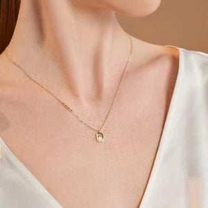 The 14K Solid Gold Natural Pearl Necklace from the Elegance Collection showcases a geometric pendant with vertical lines and a natural pearl, all suspended from a delicate hypoallergenic gold chain featuring small link details.