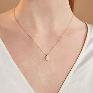 The 14K Solid Gold Natural Pearl Necklace from the Elegance Collection showcases a beautifully twisted design that cradles a natural pearl. Crafted from authentic 14K solid yellow gold, the pendant gracefully hangs on a delicate chain. Its hypoallergenic properties make it gentle for sensitive skin, all set against a white background to highlight its exquisite beauty.