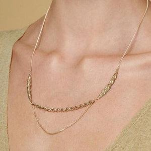 The 14K Solid Gold Succulent Necklace from the Into the Woods Collection by Erdem Akan is a sustainable jewelry piece featuring an asymmetrical design in yellow gold. It combines two distinct chain types: one with flat, leaf-like links and another with smaller, rounded links. Its delicate and elegant appearance makes it an ideal hypoallergenic jewelry choice.