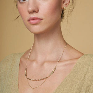 The 14K Solid Gold Succulent Necklace from the Into the Woods Collection by Erdem Akan is a sustainable jewelry piece featuring an asymmetrical design in yellow gold. It combines two distinct chain types: one with flat, leaf-like links and another with smaller, rounded links. Its delicate and elegant appearance makes it an ideal hypoallergenic jewelry choice.