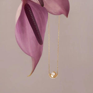 Introducing the Elegance Collection's 14K Solid Gold Natural Pearl Necklace, featuring a circular pendant showcasing a natural pearl at its center. The design includes two gold crescent shapes gently cradling the pearl, all beautifully crafted in 14K real solid yellow gold and suspended on a delicate hypoallergenic gold chain.