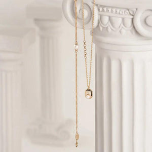 The 14K Solid Gold Natural Pearl Necklace from the Elegance Collection showcases a geometric pendant with vertical lines and a natural pearl, all suspended from a delicate hypoallergenic gold chain featuring small link details.