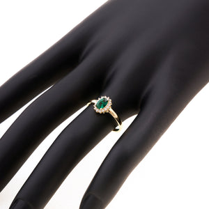 This 14K solid gold ring, named the Emerald May Birthstone Ring, features an oval green gemstone surrounded by dazzling diamonds, capturing a vintage aesthetic. The hallmark is gracefully engraved inside its smooth band.