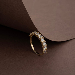 A 14K solid gold wedding ring from the Tennis Cubic Zirconia Band collection featuring a row of sparkling cubic zirconia stones, each held by prongs, elegantly showcased against a plain background.