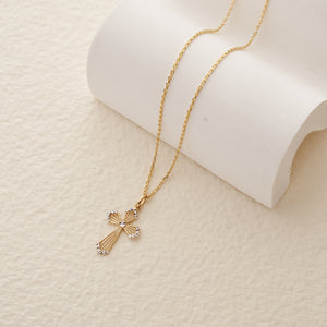 The 14K Solid Gold Tiny Cross Pendant Necklace features exquisite detailing and a central diamond-like stone, blending gold and silver tones for a captivating design. Ideal for religious occasions, it is elegantly showcased against a plain white background, exuding timeless sophistication.