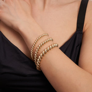 This 14K Real Solid Gold San Marco Bracelet showcases a circular design with a twisted pattern, featuring rounded, shiny links arranged in an elegant spiral. It is displayed against a plain white background.