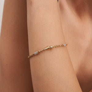 This handcrafted jewelry piece, named the 14K Solid Gold Wheat Palm Foxtail Link Bracelet CZ, showcases a twisted chain design in solid 14K gold and features four evenly spaced sections adorned with small, sparkling gemstones. The bracelet exudes a sleek and elegant appearance.