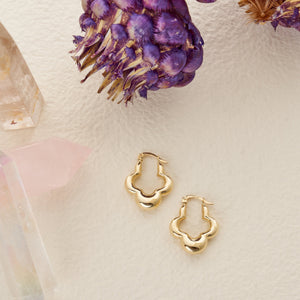 Two gold hoop earrings are on display. The first features a chunky design crafted from 14K real gold, while the second highlights a cloud-like decorative pattern. Both variations of the 14K Real Gold Thick 3 Leaf Clover Hoop Earrings gleam beautifully and come with a secure latch-back closure.