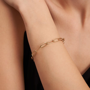 A stylish 14K gold paperclip chain bracelet featuring unique Italian paperclip-inspired elongated oval links, complete with a secure lobster clasp closure. The design skillfully combines large and small links for a modern aesthetic.