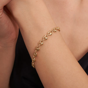 The 14K Real Gold Heart Shaped Mariner Bracelet beautifully showcases a series of linked heart-shaped elements, connected by smaller circular links that echo an anchor link chain design. Its elegant glisten stands out against a white background.