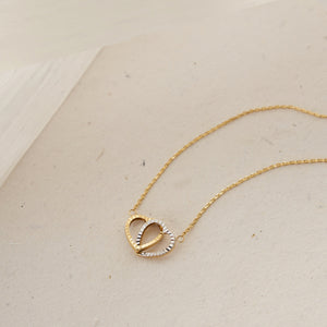 Presenting the exquisite 14K Solid Gold Interlocking Hearts Necklace, featuring two interwoven heart pendants—one crafted in gold and the other in silver—beautifully showcased against a simple white background. This necklace is an ideal couple's gift, representing unity and love.