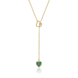 The 14K Solid Gold Heart Lariat Necklace features a sleek and elegant design, with a small heart-shaped malachite pendant at the end. The chain includes an interlocking heart design near the top, enhancing its overall intrigue.