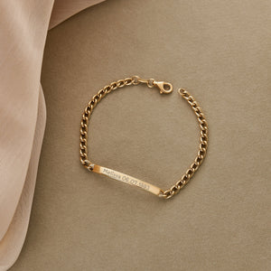 Presenting the 14K Solid Gold Nameplate ID Bracelet, an elegant customizable piece featuring a plain rectangular bar crafted from solid gold. The bracelet is secured with a lobster clasp and showcases a classic Cuban curb chain design with alternating small and larger interlocking links for a timeless style.