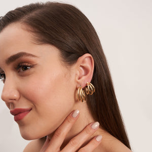 A pair of 14K Solid Real Gold Triple Ropes Hoop Earrings is showcased, with one earring standing upright while the other rests flat. This composition highlights its round shape and intricate clasp detail against a pristine white background—perfectly capturing elegance and simplicity.