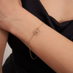 The 14K Solid Gold Minimal Heart and Circle Interlocking Bracelet highlights a delicate design with heart-shaped and circular pendants, the latter adorned with small white stones. This handmade jewelry piece features an adjustable chain and a lobster clasp closure.